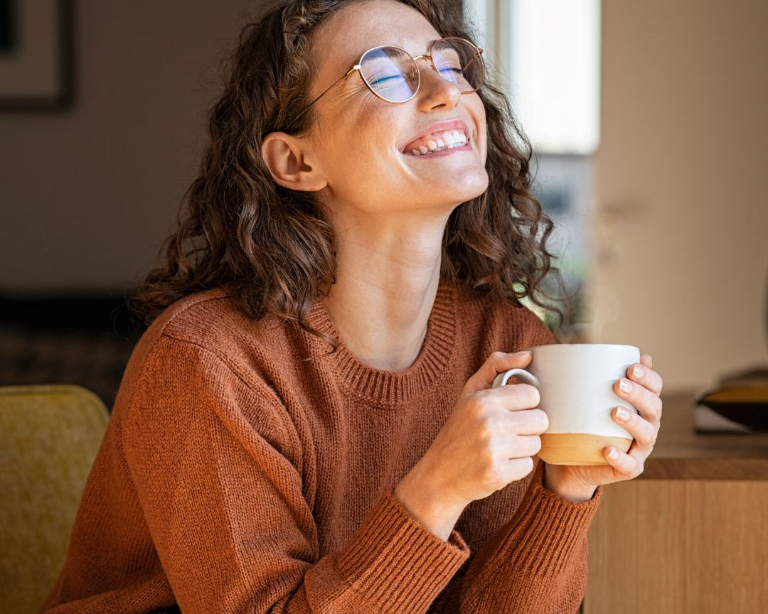 femme heureuse et souriante qui boit du thé ou une infusion