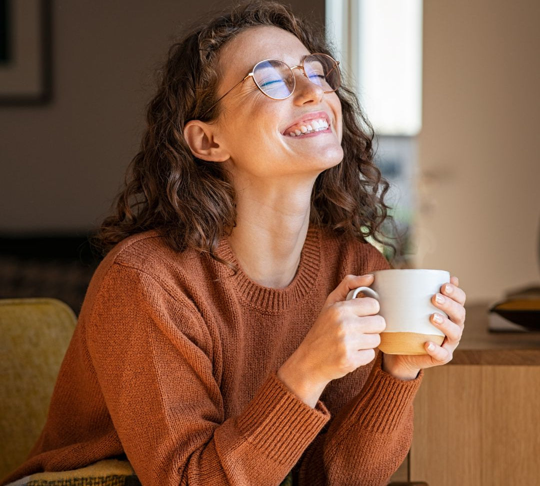 femme heureuse et souriante qui boit du thé ou une infusion