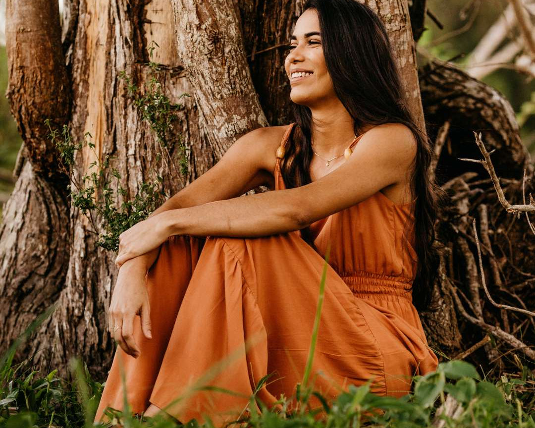 oria nature femme assise dans l'herbe qui sourit