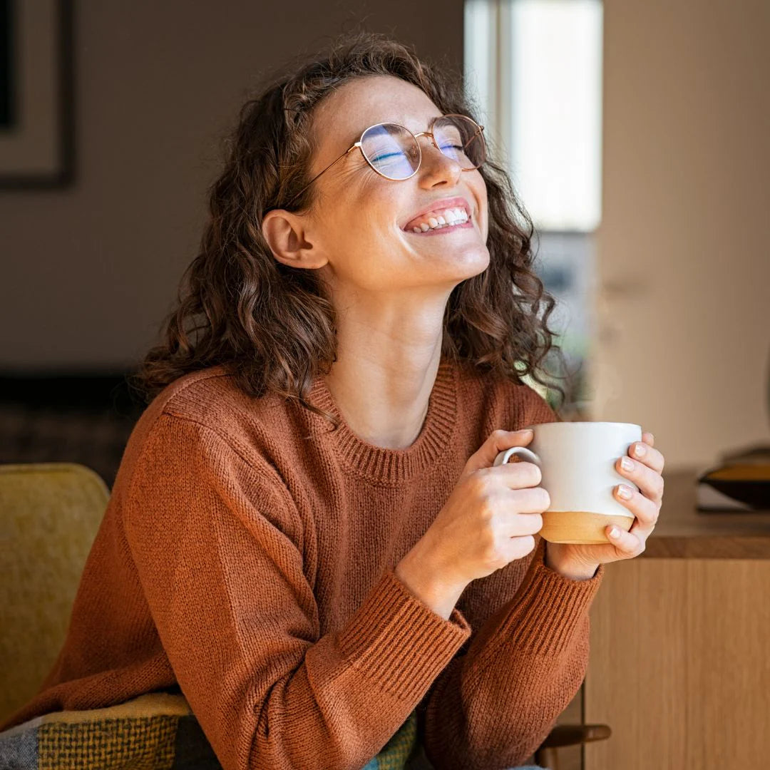 Femme souriante assise sur une canapé avec une tasse à la main