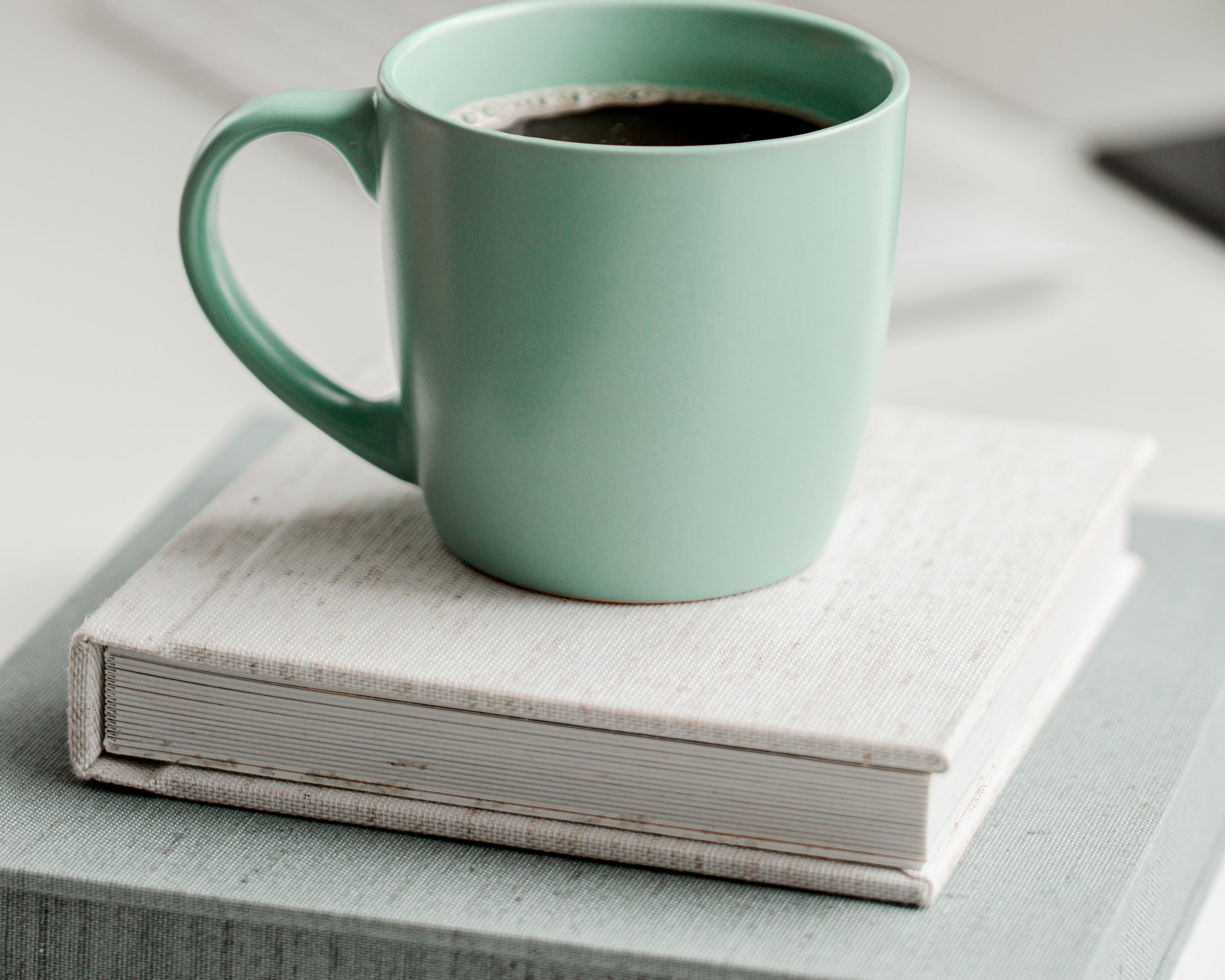 mint-green-mug-full-of-black-coffee-on-top-of-books.jpg